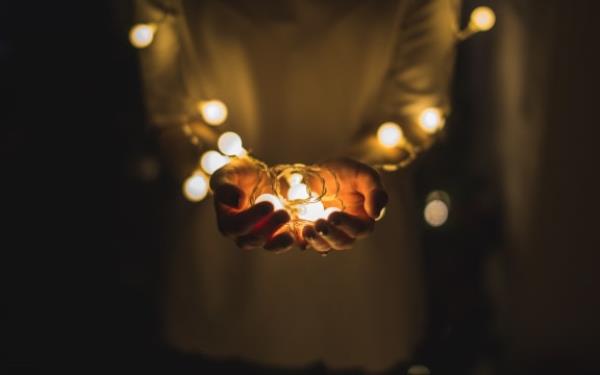 A person cupping some Christmas lights in their hands